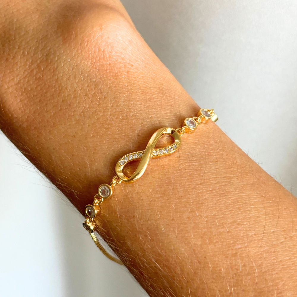 Gold Infinity Bracelet with round crystal accents worn on wrist